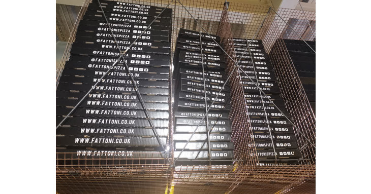 Industrial style shelving holds pizza boxes, ready for delivery.